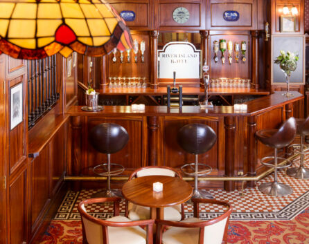 Cosy hotel bar with wooden decor and seating, featuring River Island Hotel signage.