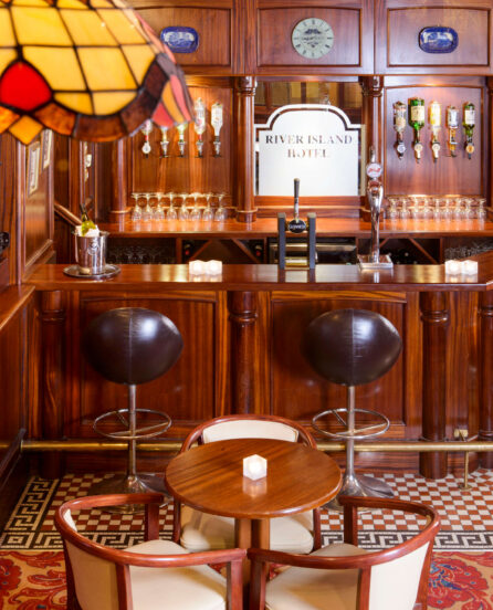Cosy hotel bar with wooden decor and seating, featuring River Island Hotel signage.
