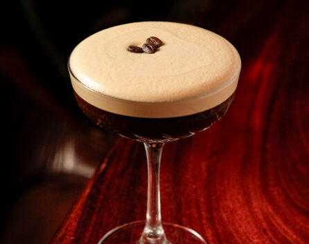 Elegant espresso martini on a polished wooden table, creating a cosy atmosphere.