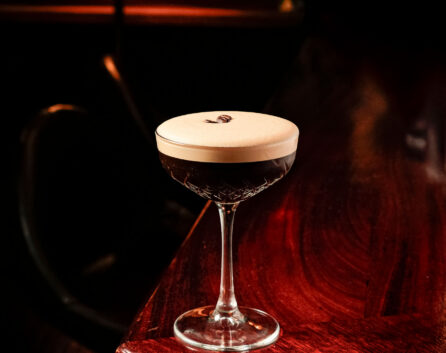 Elegant cocktail on a polished wooden bar in River Island Hotel's cosy lounge.