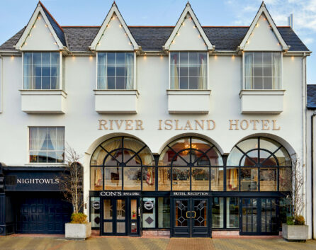 Charming River Island Hotel exterior with warm lighting, inviting groups and families.