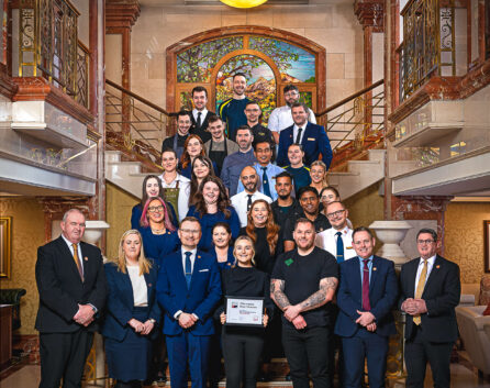 Group of hotel staff posing on a grand staircase in River Island Hotel lobby.