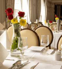 Elegant dining room at River Island Hotel with set tables and floral centrepieces.