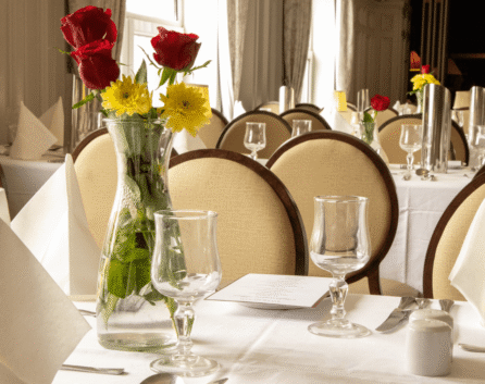 Elegant dining room at River Island Hotel with set tables and floral centrepieces.