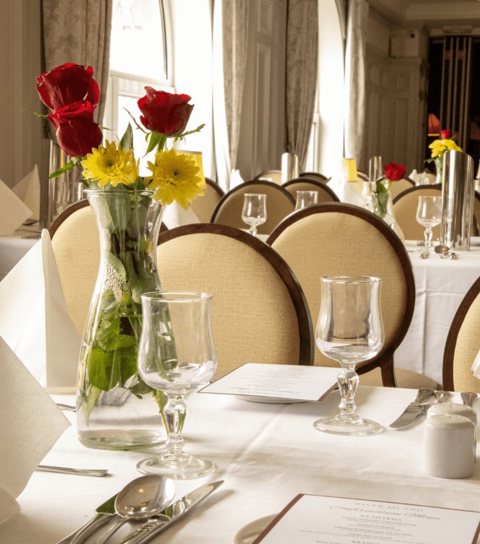 Elegant dining room at River Island Hotel with set tables and floral centrepieces.