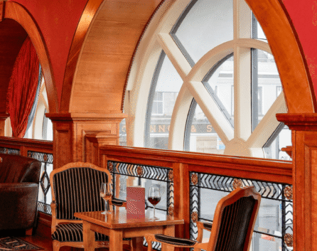 Cosy lounge with wooden arches at River Island Hotel, featuring elegant chairs and wine glasses.