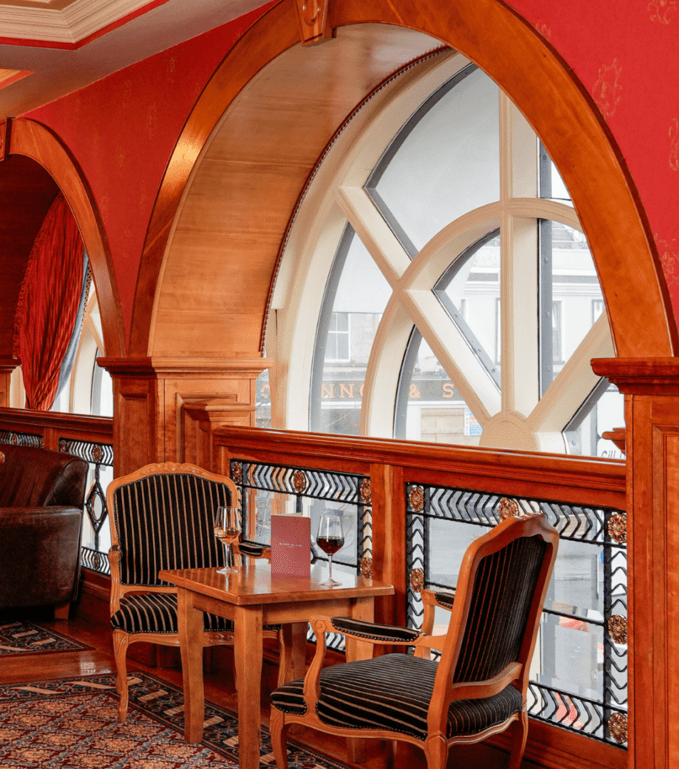 Cosy lounge with wooden arches at River Island Hotel, featuring elegant chairs and wine glasses.
