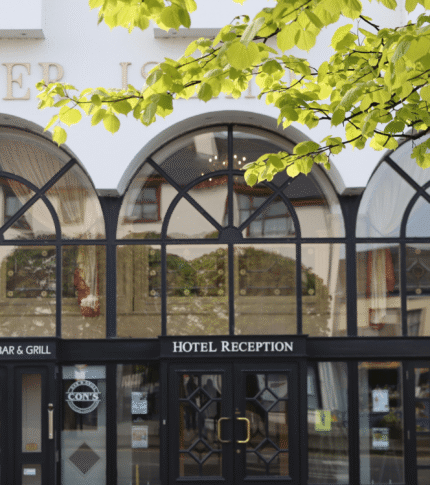 Elegant entrance of River Island Hotel with signs for reception and Con’s Bar & Grill.