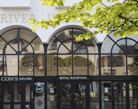 Elegant entrance of River Island Hotel with signs for reception and Con’s Bar & Grill.
