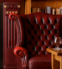 Cosy lounge with red leather armchair by fireplace in River Island Hotel.