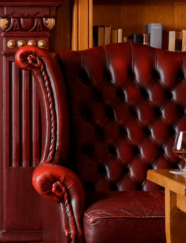 Cosy lounge with red leather armchair by fireplace in River Island Hotel.