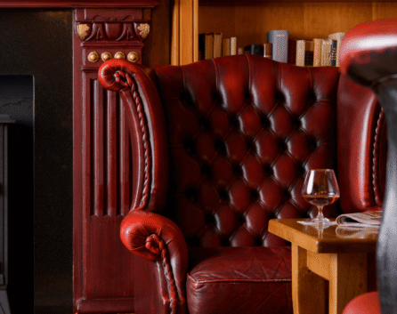 Cosy lounge with red leather armchair by fireplace in River Island Hotel.