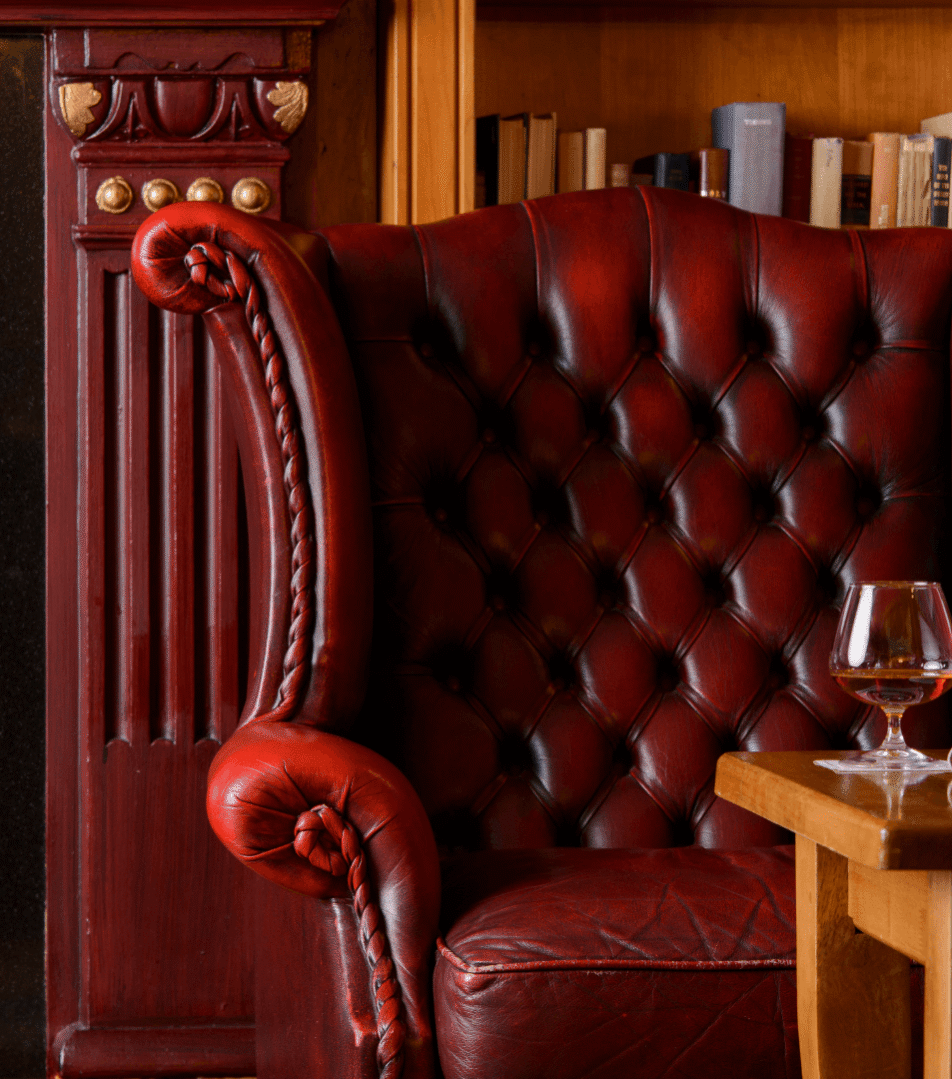 Cosy lounge with red leather armchair by fireplace in River Island Hotel.