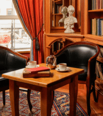 Cosy hotel lounge with books, armchairs, and tea set; ideal for relaxation.