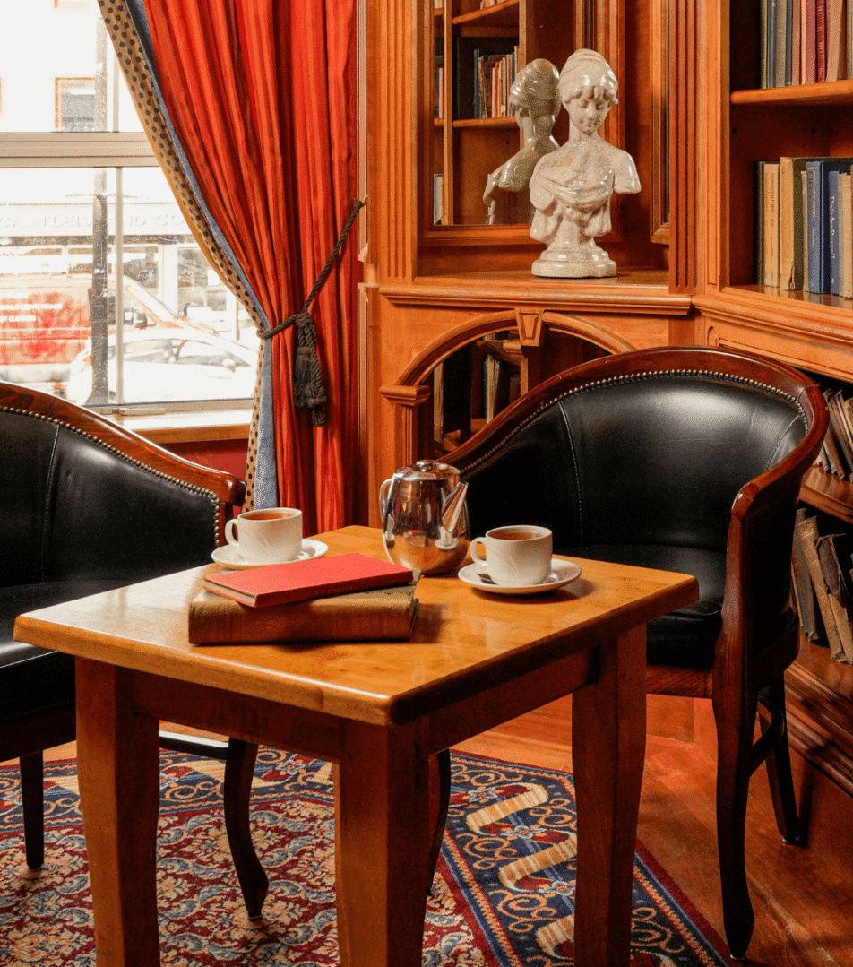 Cosy hotel lounge with books, armchairs, and tea set; ideal for relaxation.