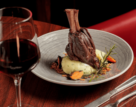 Elegant dining with lamb shank and red wine at River Island Hotel.
