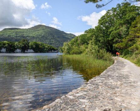 Family walking by a serene lake with mountain view at River Island Hotel, Kerry.