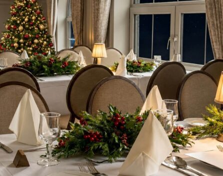 Festive dining room with decorated tables and a Christmas tree at River Island Hotel.