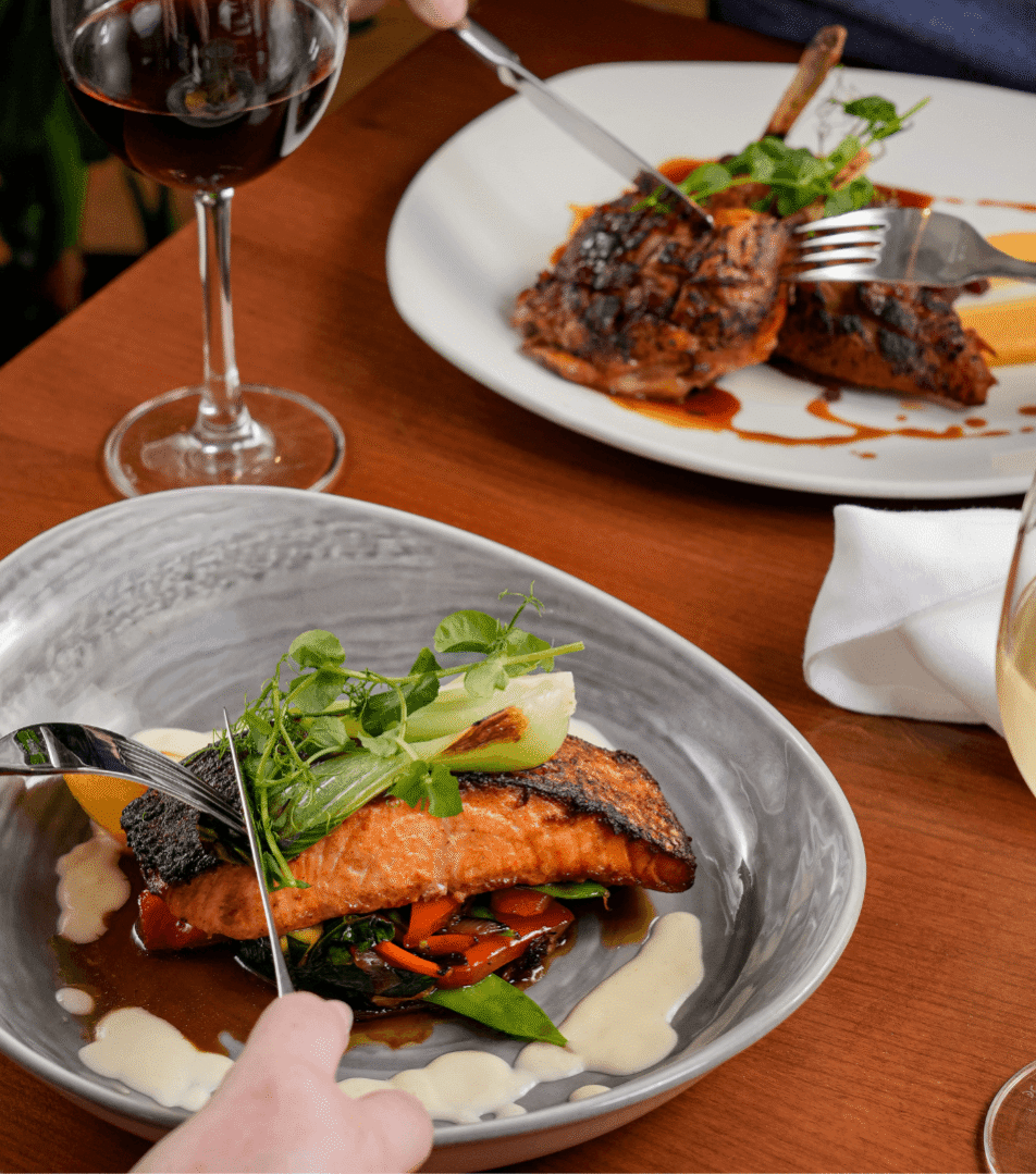 Couple dining elegantly at River Island Hotel, savouring gourmet dishes with wine.