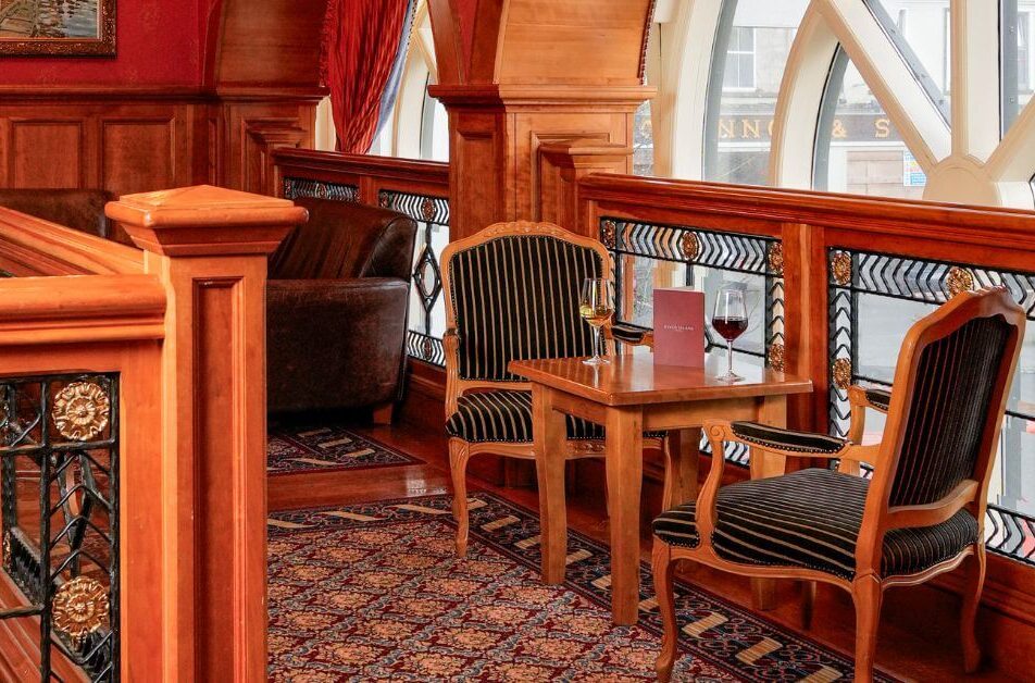 Cosy hotel lounge with wooden decor and wine glasses, ideal for relaxation.
