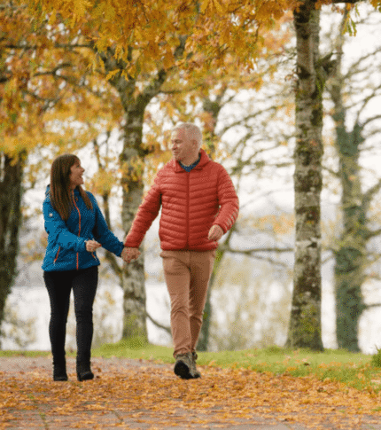 Couple walking hand in hand on autumn path at River Island Hotel.