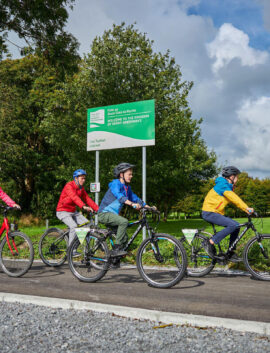 Family cycling near River Island Hotel, lush greenery surrounds them.