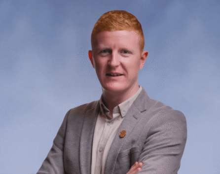 A friendly hotel host in a smart blazer welcomes guests to River Island Hotel.
